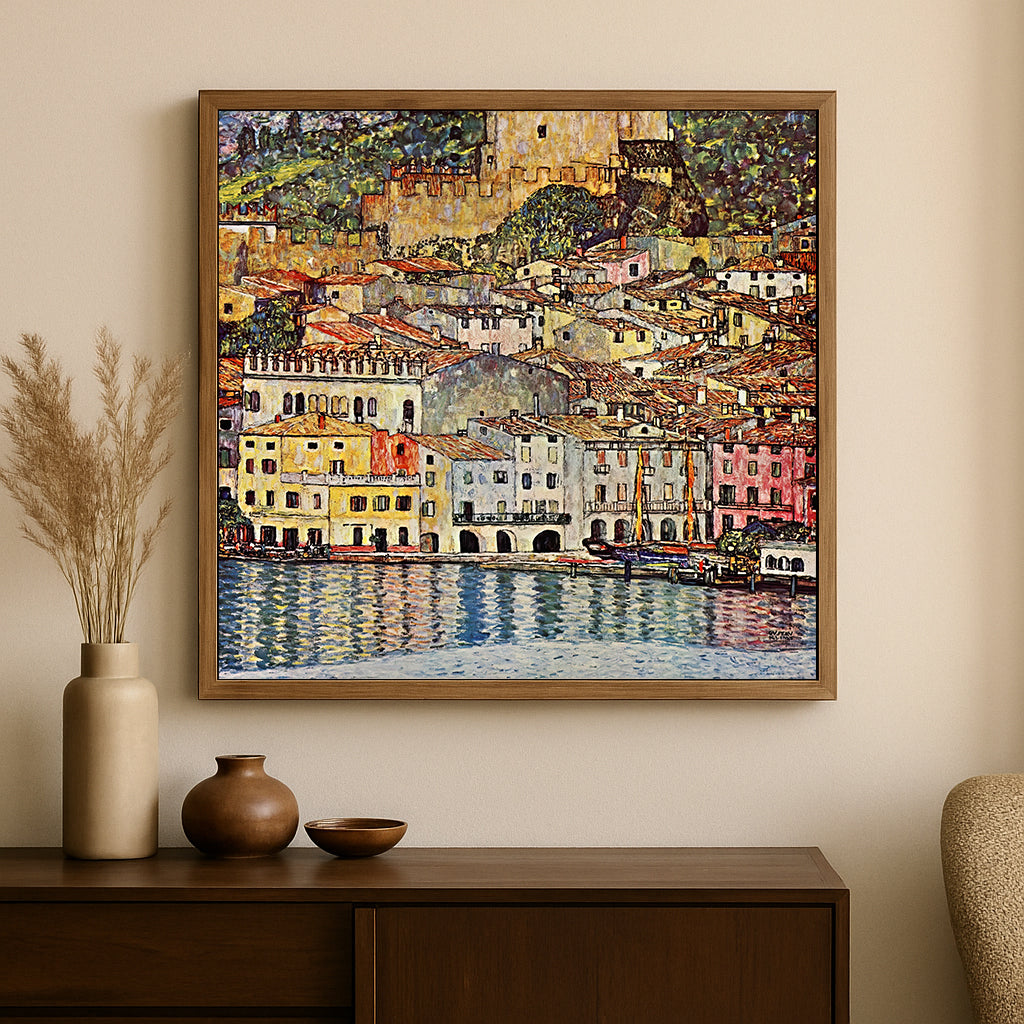A framed square canvas print of an impressionist coastal town painting hangs on a beige wall above a dark wood console table with decorative vases.