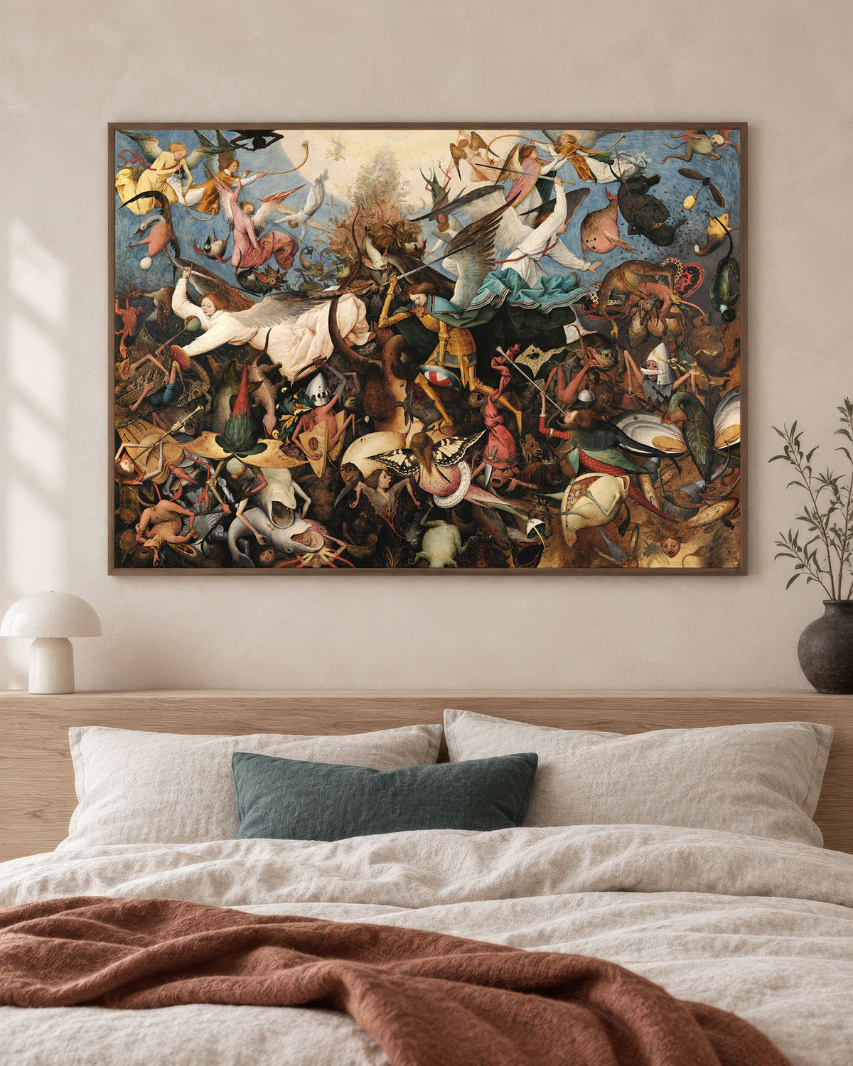 A framed art print of Pieter Bruegel's chaotic painting 'The Fall of the Rebel Angels' displayed on a beige wall above a bed with neutral-toned bedding and a rust-colored throw blanket.