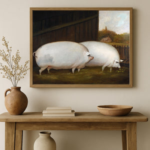 A framed painting of two white pigs in a barn hangs on a beige wall above a wooden console table styled with a terracotta vase, books, and a bowl.
