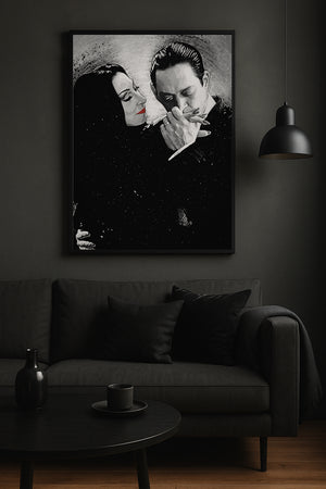 A framed black and white art print of a classic movie scene, featuring a woman with red lips and a man smoking a cigarette, displayed on a dark gray wall above a matching dark gray sofa in a moody room.