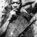 Black and white watercolor-style portrait print of jazz saxophonist John Coltrane holding a saxophone, with his signature visible in the lower right corner.
