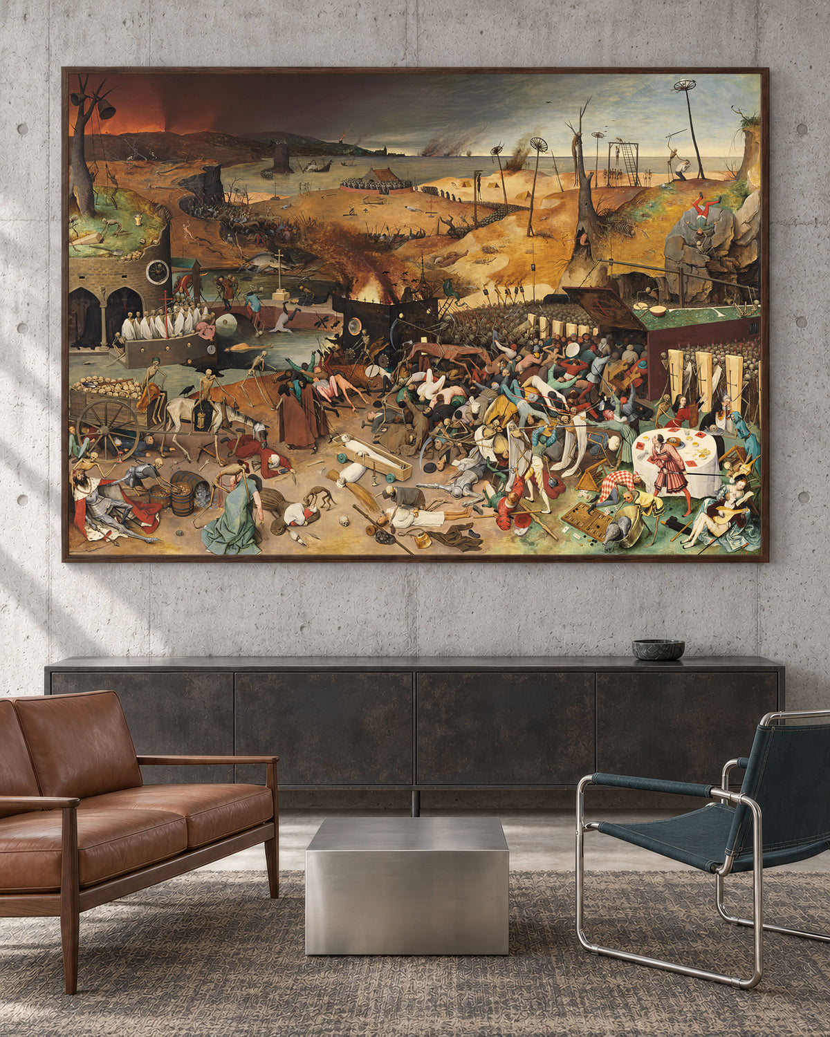 A large framed painting of a chaotic historical battle scene hangs on a textured gray concrete wall above a dark cabinet in a modern living room setting with a brown leather sofa and a blue chair.